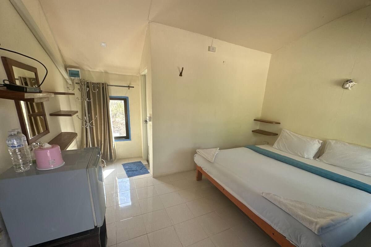 Une chambre à coucher avec un lit, un bureau, une chaise, un miroir, une fenêtre et une porte.