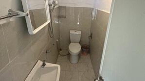 Une petite salle de bain avec un lavabo blanc, des toilettes et une douche.