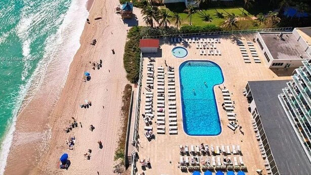 An aerial view of a resort with a beach, a swimming pool, and multiple buildings. - One Step to The Beach (Sunny Isles)