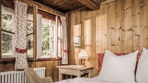 Una habitación acogedora de madera con una cama, una mesita de noche, una lámpara y una ventana con cortinas.
