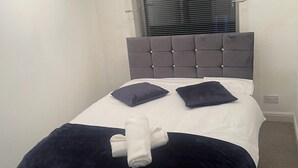 A neatly made bed with a grey headboard, two pillows, and a rolled towel. - Cozy 3 Bedrooms Birmingham House With Pool Table (Birmingham)
