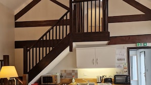 A kitchen with wooden beams, white cabinets, a microwave, a toaster, and a sink. - Stay Norwich Apartments Lodge 6 (Norwich)