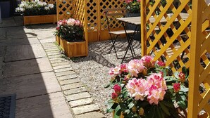 Un patio con cerca de madera, una mesa, sillas y macetas de flores.