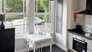 A compact kitchen with a dining area, large windows, and a view of the street. - Stay Norwich Apartments Riverside House Apart-1 (Norwich)