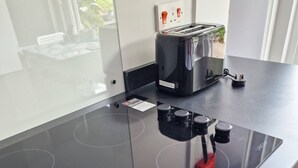 A modern kitchen with a black induction cooktop, a toaster, and a kettle.