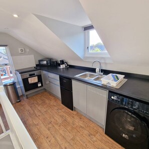 A compact kitchen with a dishwasher, oven, and a small window above the sink.