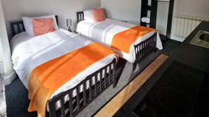 A bedroom with two beds, a small desk, and a radiator. - Stay Norwich Apartments Riverside House Apart-2 (Norwich)