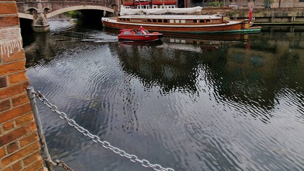 A canal with a red boat docked near a brick building with a sign that reads "PUS." - Stay Norwich Apartments Cathedral Quarter (Norwich)