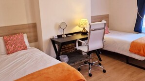 A hotel room with two beds, a desk with a chair, a lamp, and a picture on the wall. - Stay Norwich Apartments Cathedral Quarter (Norwich)
