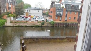 A view of a canal with a row of buildings on one side and a row of parked cars on the other. - Stay Norwich Apartments Cathedral Quarter (Norwich)