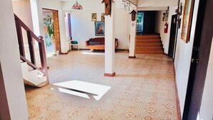 Un pasillo amplio con piso estampado, una escalera y un banco.