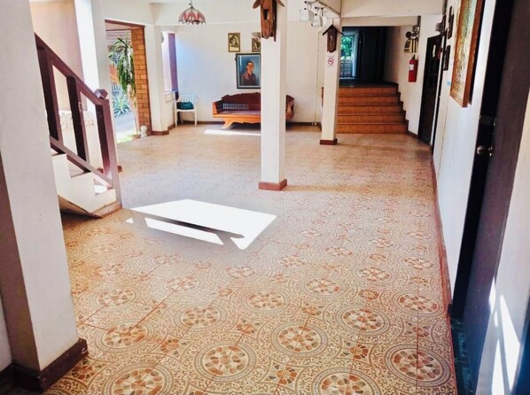 Un pasillo amplio con piso estampado, una escalera y un banco.