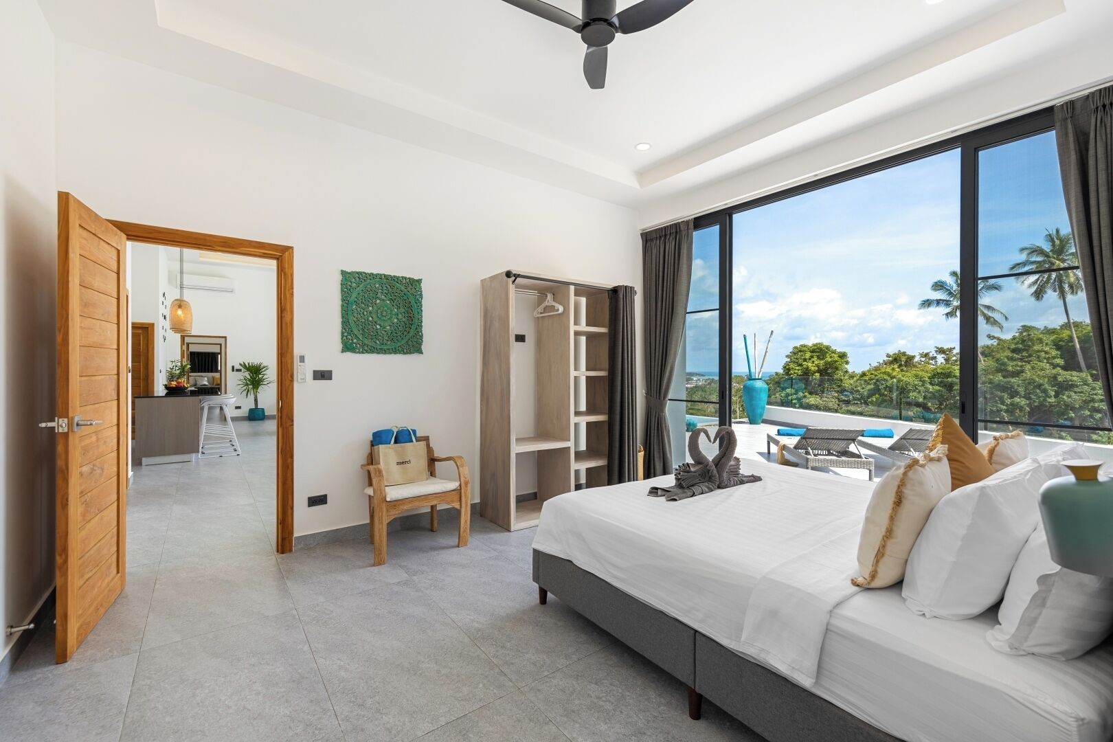 A modern hotel room with a large bed, a seating area with a view, a wardrobe, and a balcony with a view.