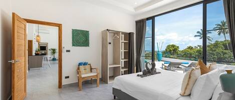 A modern hotel room with a large bed, a seating area with a view, a wardrobe, and a balcony with a view.