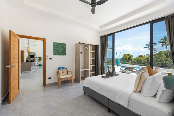 Ein modernes Hotelzimmer mit einem großen Bett, einer Sitzecke mit Blick, einem Kleiderschrank und einem Balkon mit Aussicht.