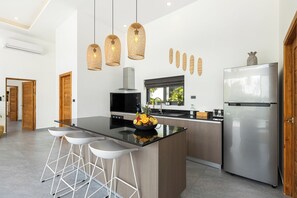 A modern kitchen with a central island, stainless steel appliances, and a dining area with bar stools.