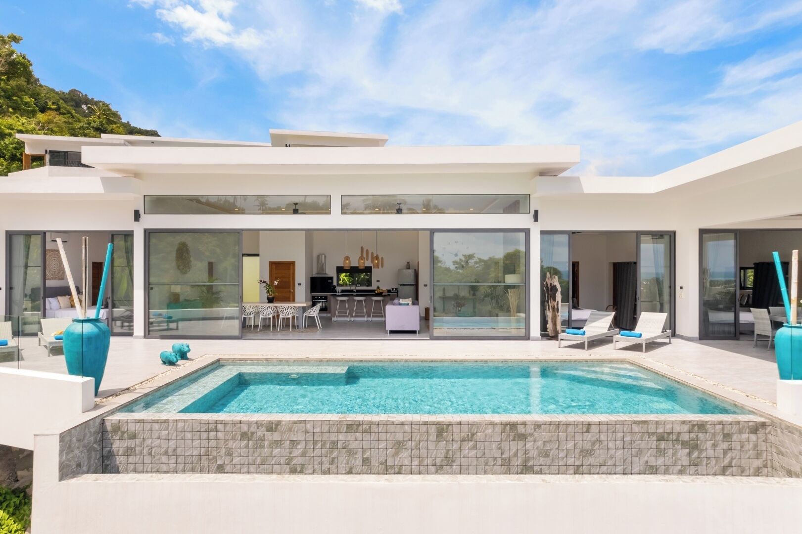 Une maison moderne dotée d’une piscine, d’un coin repas et d’une cuisine.