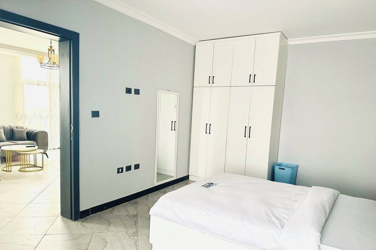 Ein modernes Schlafzimmer mit einem großen Bett, einem Kleiderschrank und einem Spiegel.
