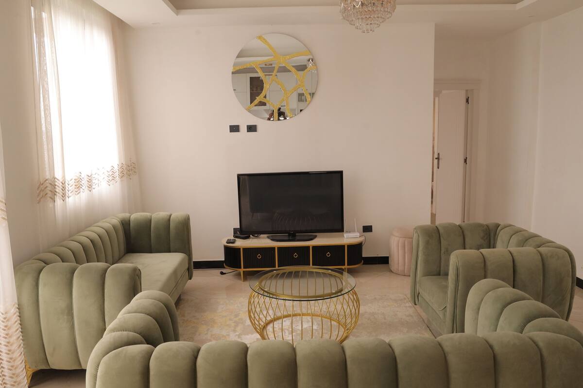 Ein Wohnzimmer mit einer Sofagarnitur, einem Fernseher und einem dekorativen Spiegel.