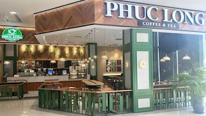 A coffee shop named PHUC LONG with a modern interior, including a counter, seating area, and decorative lighting.