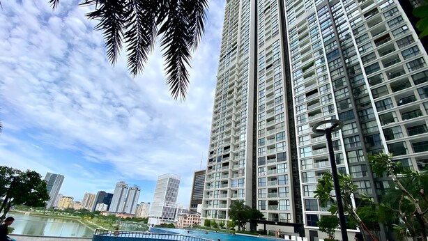 A swimming pool surrounded by high-rise buildings, with people swimming and walking around.