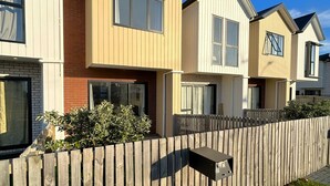 Een rij moderne, twee verdiepingen tellende huizen, gescheiden door een houten hek.