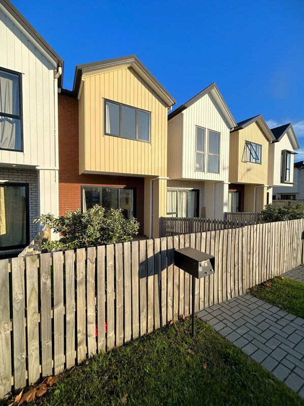 A row of modern, two-story houses with a wooden fence separating them. - Entire Modern 2-Bedroom Townhouse, 10 min to Airport/Sylvia Park (Auckland)