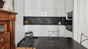 A modern kitchen with white cabinets, a marble countertop, and a wooden sideboard.