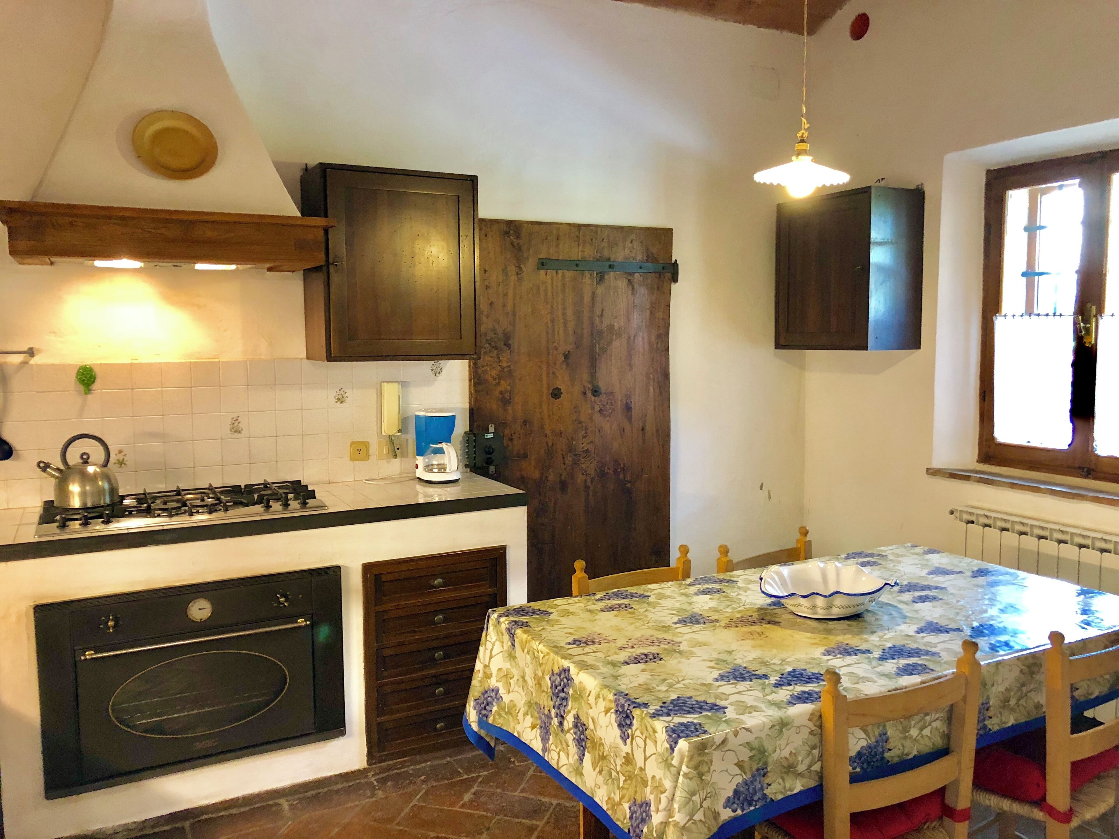 Una cocina con estufa a gas, horno y una mesa con mantel floreado.