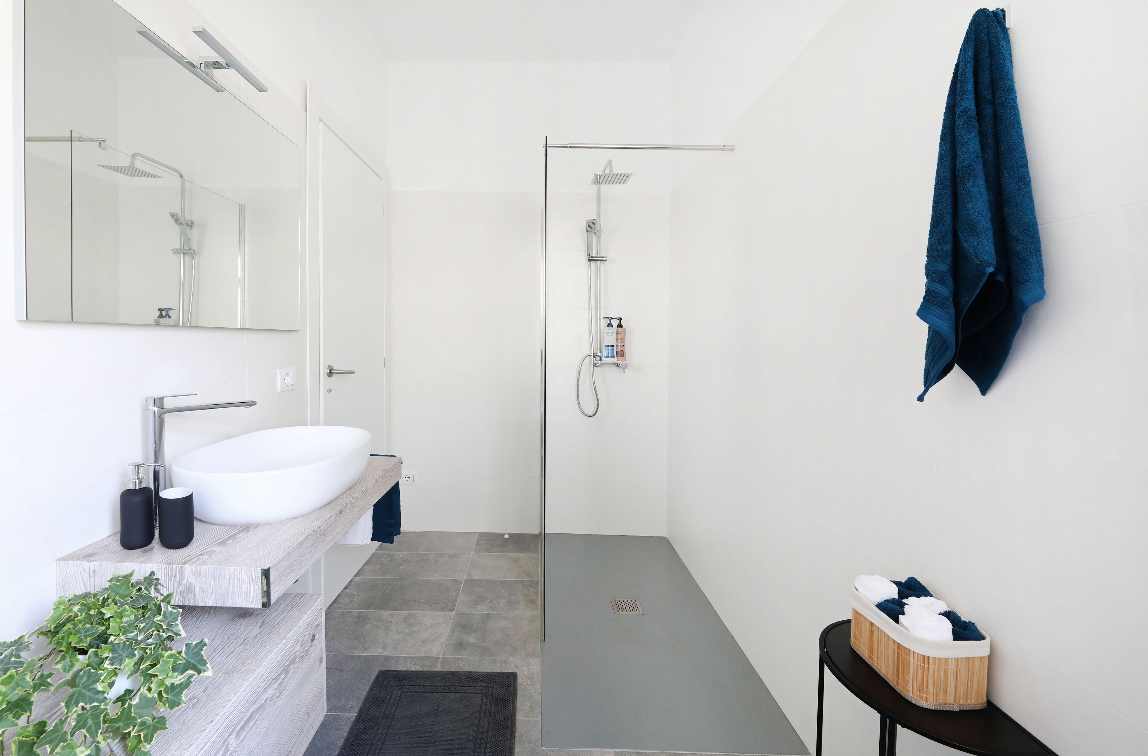 A modern bathroom with a white sink, a glass-enclosed shower, and a towel rack.