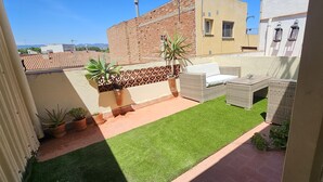 A rooftop patio with a small lawn, wicker furniture, and potted plants. - Ático en Cambrils (Cambrils)