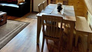 A cozy cabin interior with a wooden ceiling, a sofa with a plaid blanket, a dining table with chairs, and a window with curtains. - Waterfront -Cozy Camp Triangle (Stratford)
