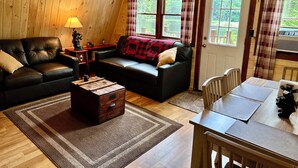 A cozy cabin interior with a leather sofa, a wooden table, and a ceiling fan. - Waterfront -Cozy Camp Triangle (Stratford)