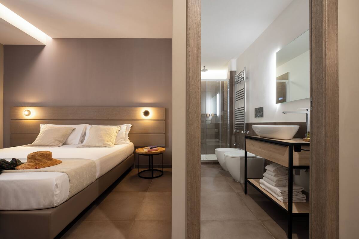 A modern bedroom with a large bed, bedside table, and a small round table.