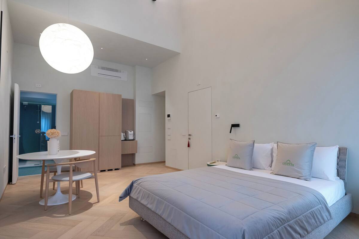 Moderni hotellihuone, jossa on sänky, pyöreä pöytä ja tuoli.