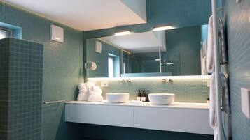 A modern bathroom with a large mirror, two sinks, and a toilet.