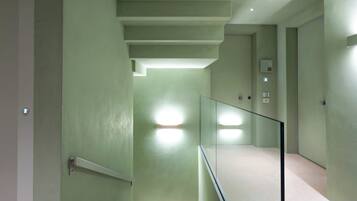Un intérieur moderne avec un escalier, une rampe en verre et des murs verts.