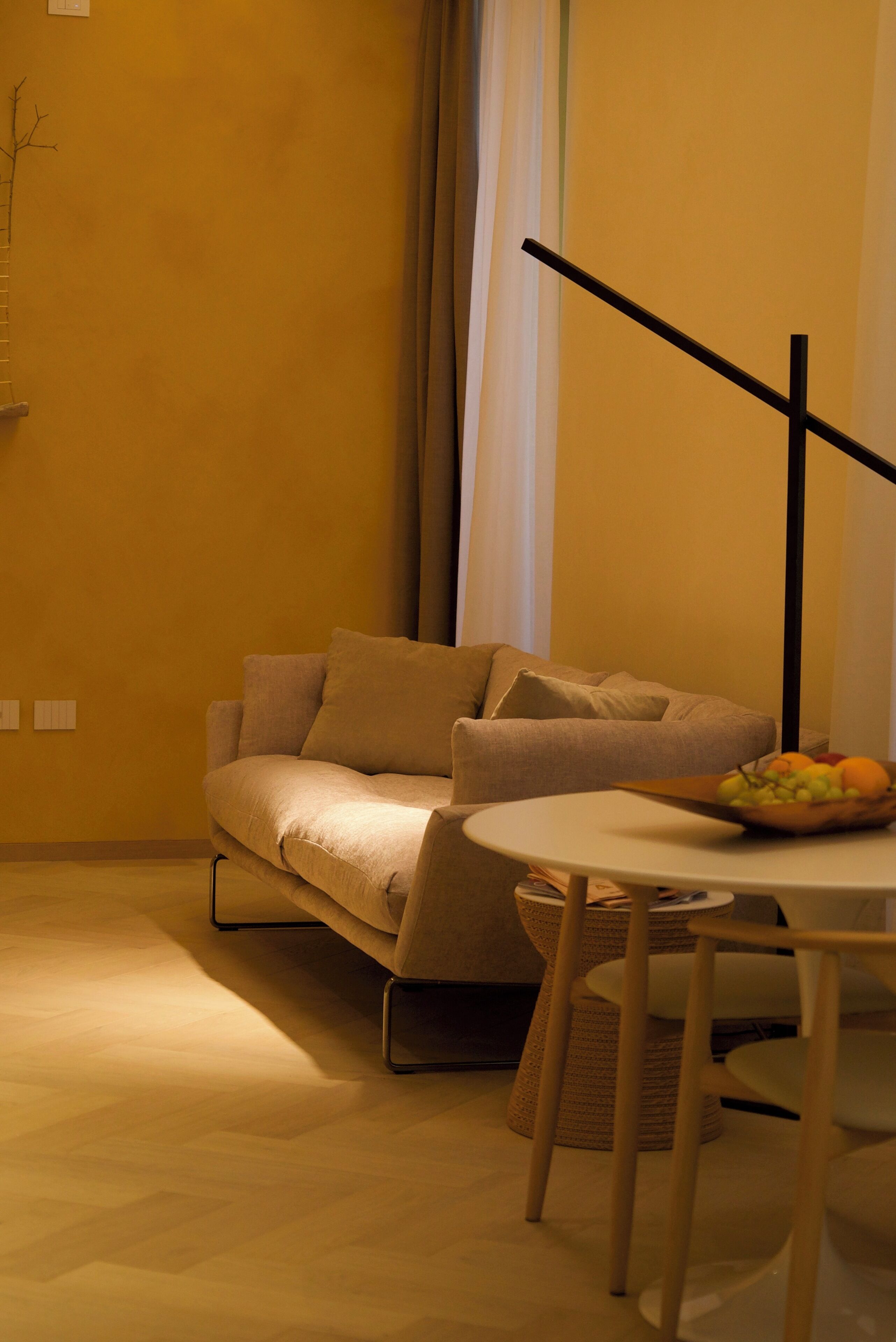A cozy living room with a sofa, a small round table, and a bowl of fruit.