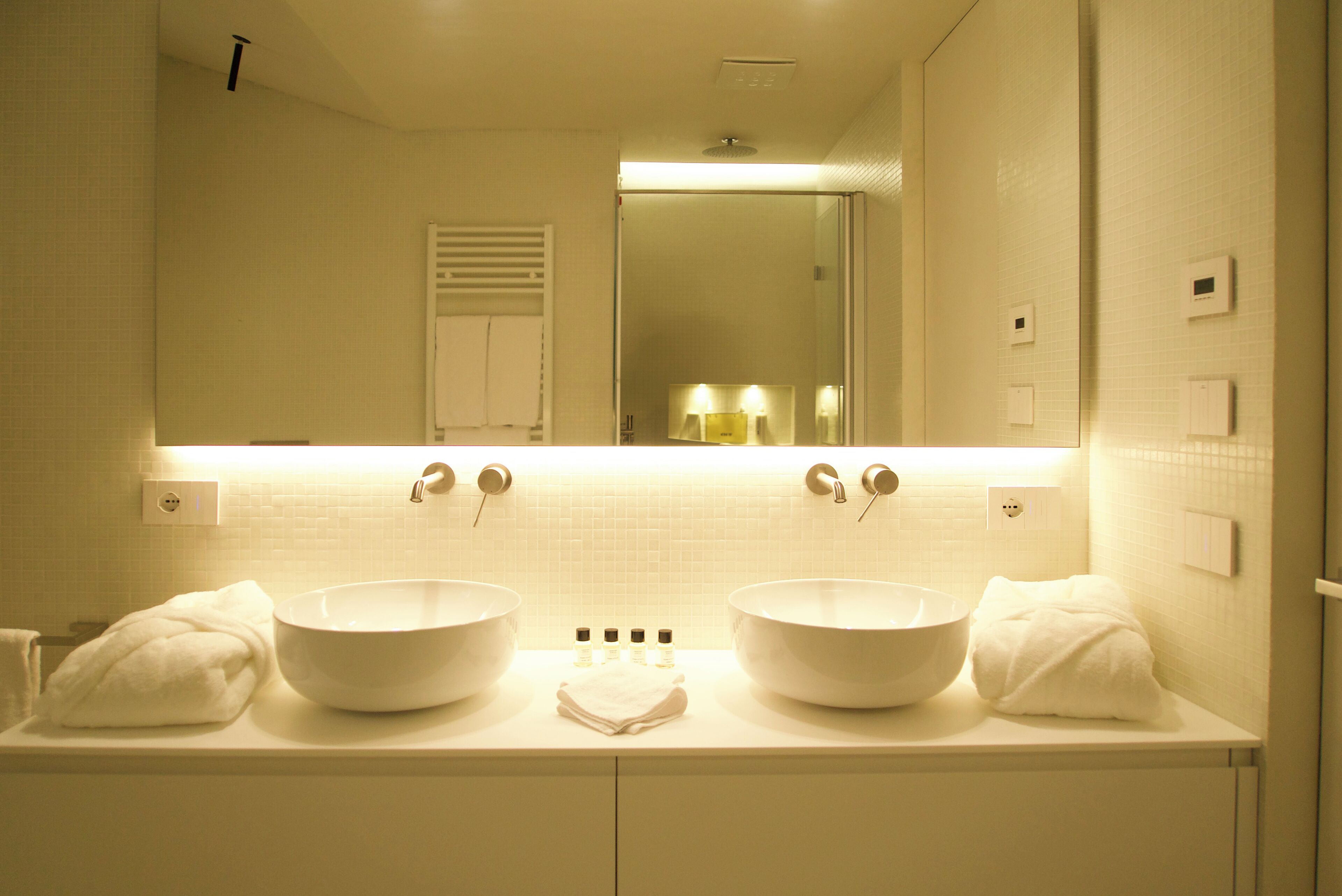 A bathroom with two large white sinks, a mirror above, and a towel rack.