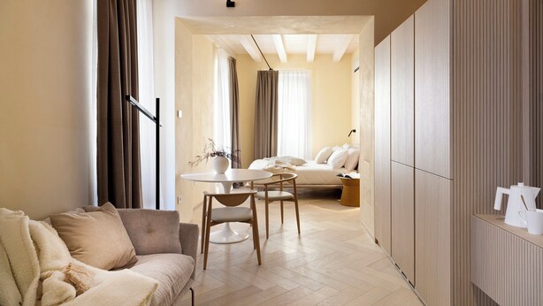 A modern living room with a sofa, a dining table with chairs, a bed, and a large wardrobe. - Palazzo Ciopeta (Verona)