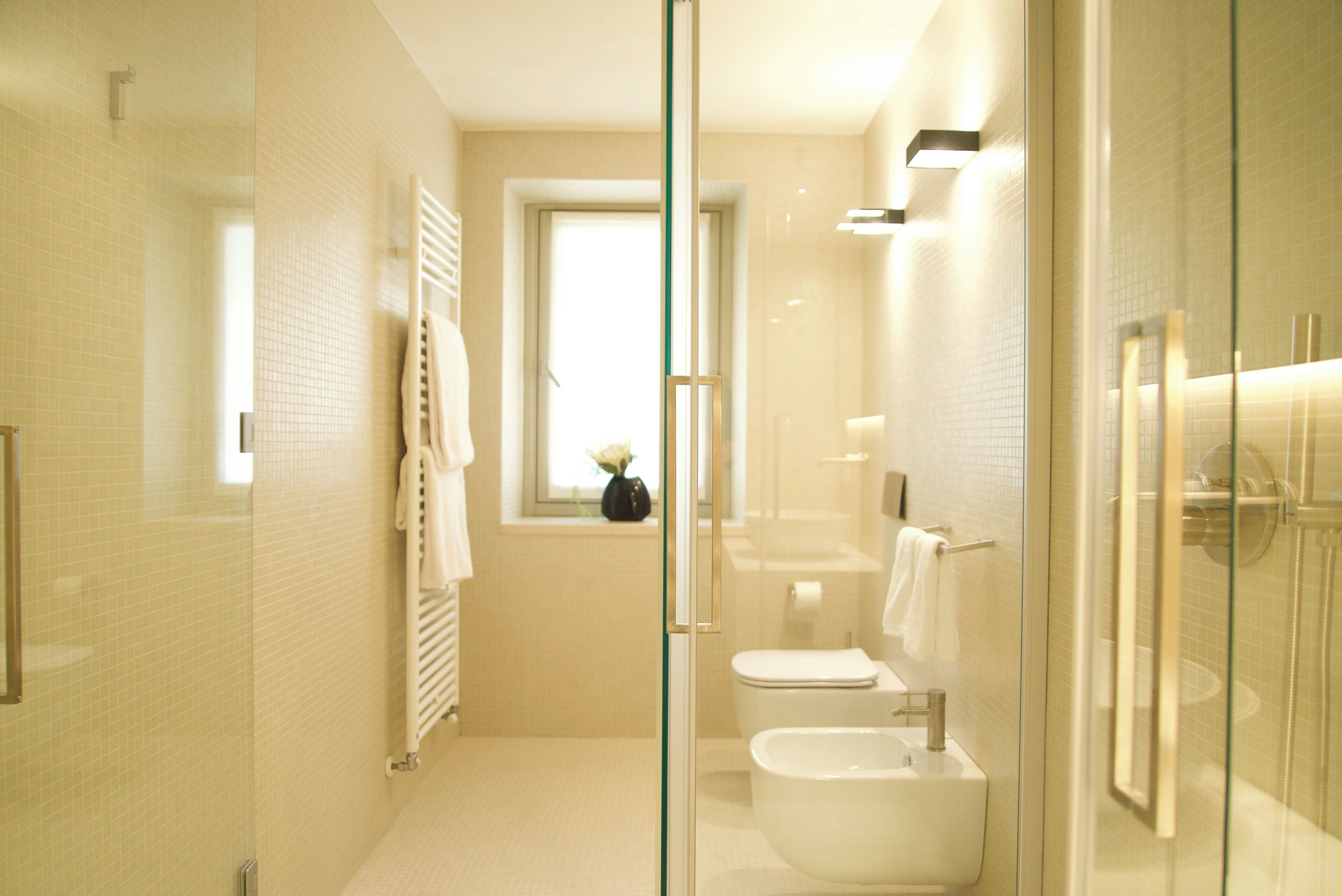 A modern bathroom with a glass shower enclosure, a toilet, a bidet, and a sink.