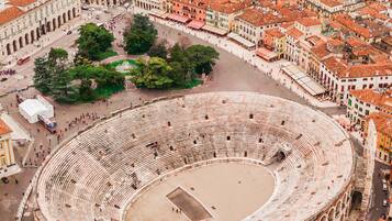 An aerial view of a historic city with a prominent circular building, likely a theater, surrounded by densely packed buildings and a river.