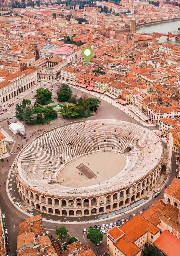An aerial view of a historic city with a prominent circular building, likely a theater, surrounded by densely packed buildings and a river.