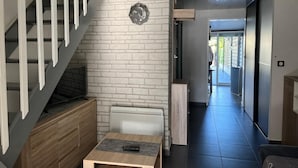 Un interior moderno con una escalera, una chimenea, una zona de comedor y vistas a través de un ventanal.