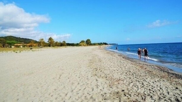 Una amplia playa de arena con algunas personas caminando por la orilla.