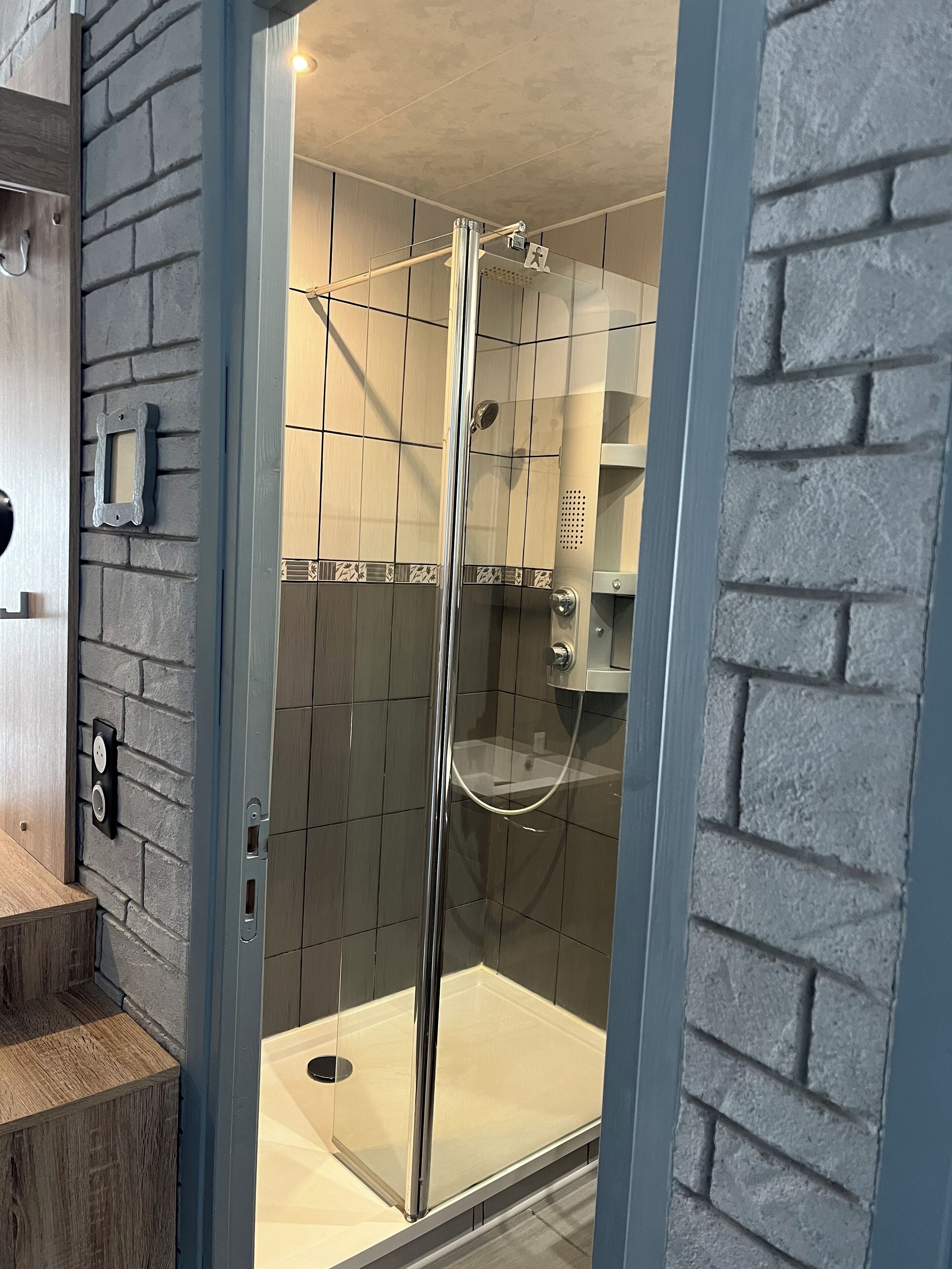 A modern shower enclosure with a glass door, a showerhead, and a control panel.
