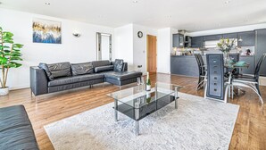 Un salon moderne avec une table basse en verre, un canapé en cuir et un coin repas comprenant une table et des chaises en verre.