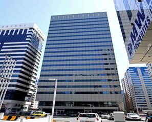 Un immeuble moderne de grande hauteur, doté d’une façade à fenêtres disposées en réseau et d’un toit plat.
