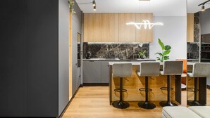Uma cozinha moderna com armários de madeira, painel de fundo de mármore e banquetas.