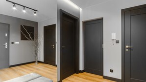 Corredor moderno com piso de madeira, portas escuras e decoração minimalista.